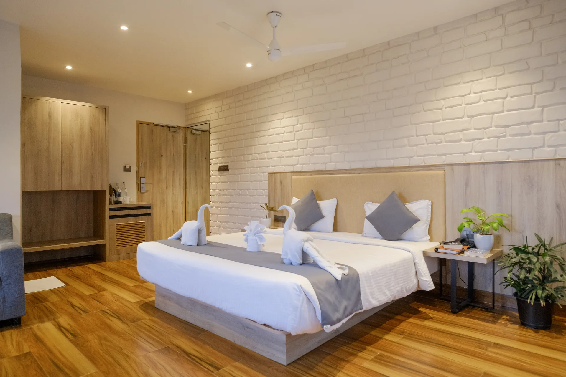 Guest room with a double bed, decorative towel arrangement and seating beside the window at Firangipani Ecosuites