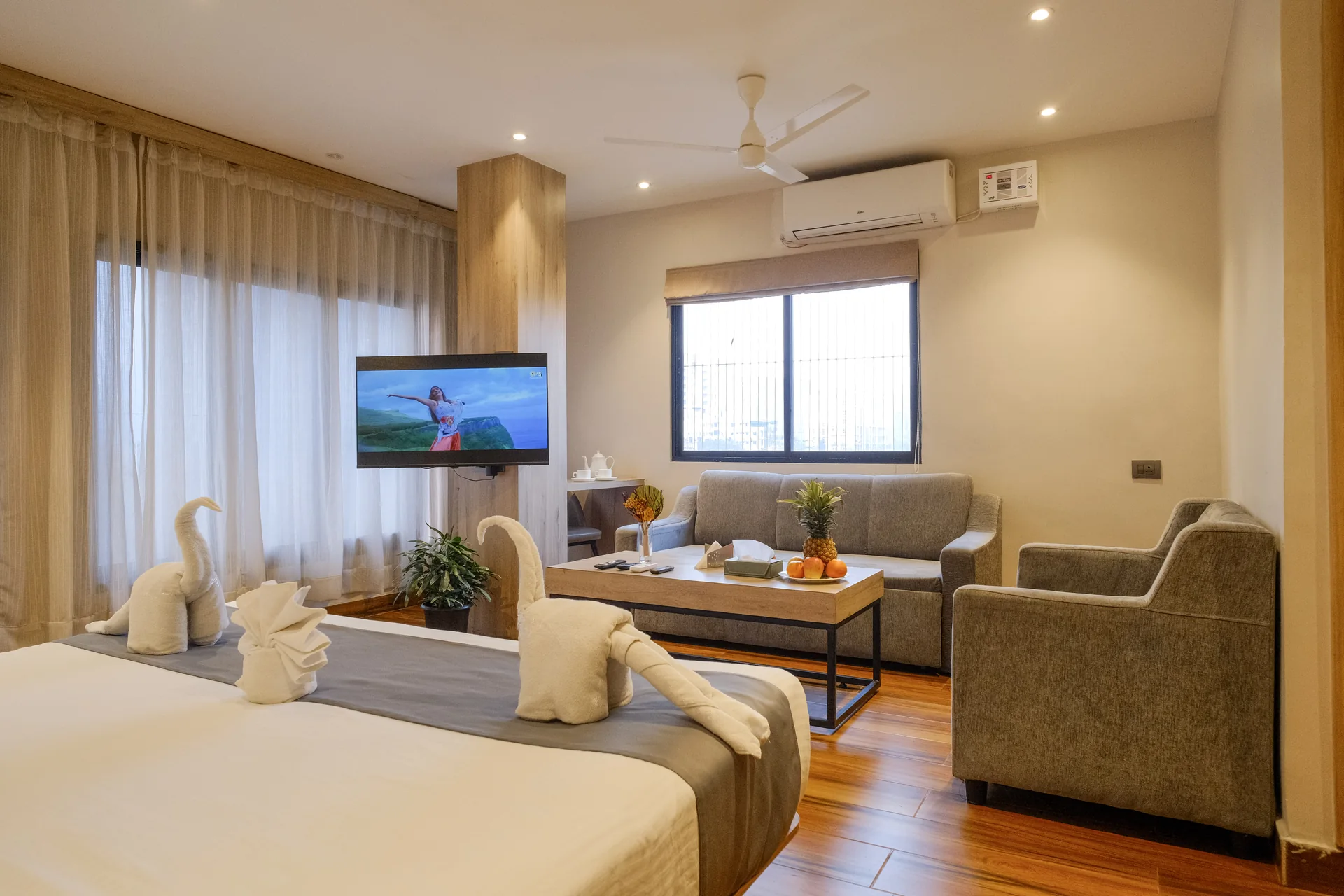 Luxury Suite with a sofa, coffee table, double bed and large windows at Firangipani Ecosuites in New Town, Kolkata