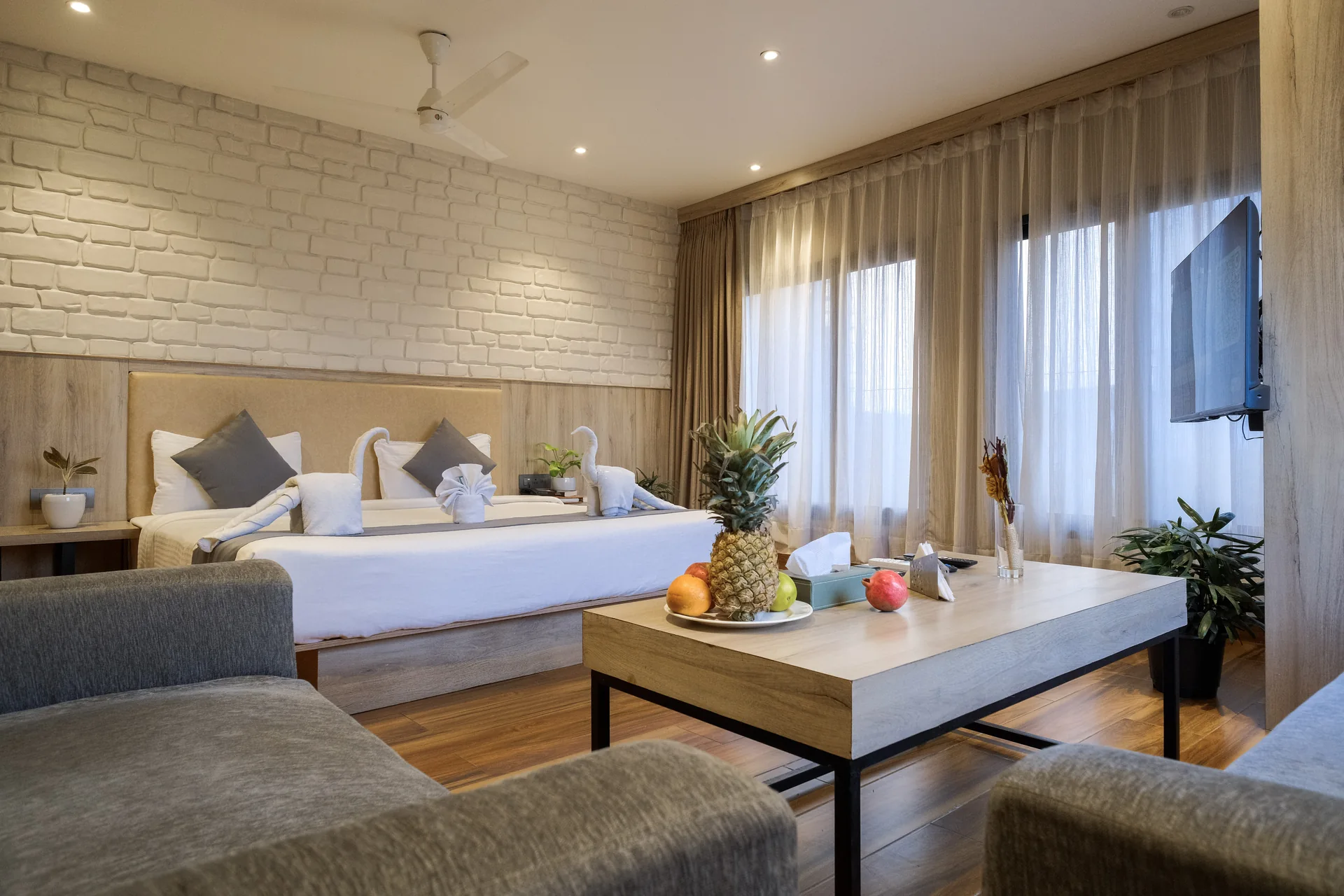 Suite with a double bed, textured white wall, sofa and fruit on the coffee table at Firangipani Ecosuites