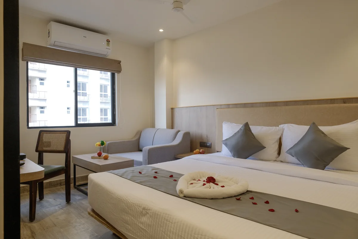 Junior Suite with a double bed, armchair and window at Firangipani Ecosuites