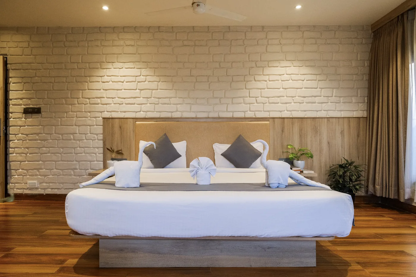 Luxury Suite bed with decorative towels, grey pillows and a wooden headboard